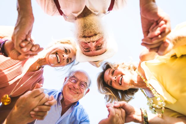 four older people holding hands in a circle